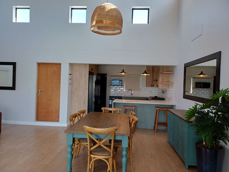 Open-plan living and dining area featuring a modern kitchen with a breakfast bar, subway tile backsplash, and high ceilings with clerestory windows.