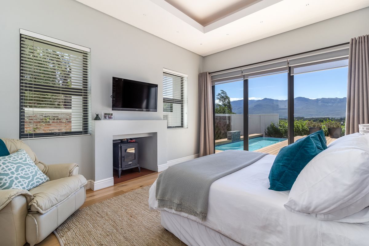 Spacious bedroom featuring a built-in fireplace, recessed ceiling lighting, and large sliding glass doors opening onto a private deck with pool and mountain views.
