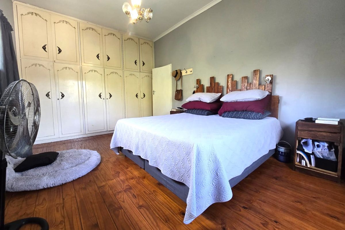 A bedroom featuring polished hardwood flooring and extensive built-in cabinetry with classic detailing.