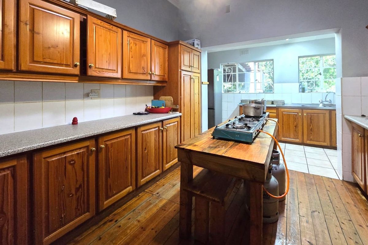 Spacious kitchen featuring extensive wooden cabinetry, laminate countertops, tiled backsplash, and timber flooring, offering a functional layout with ample storage and preparation space.
