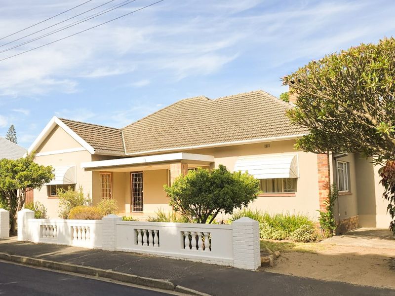 A well-maintained single-story residential home featuring a tiled roof, plastered facade, and a classic front boundary wall with a covered entrance porch.