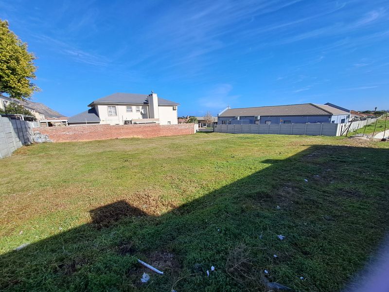 A vacant residential plot featuring established perimeter boundary walls and surrounding residential properties.