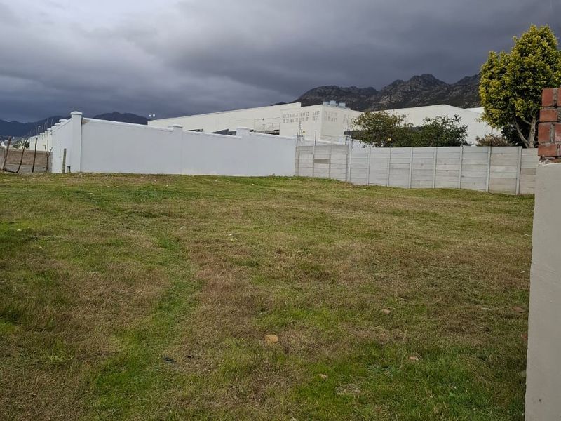 A vacant residential plot featuring grassed terrain and established perimeter walling, offering a clear space for future development.