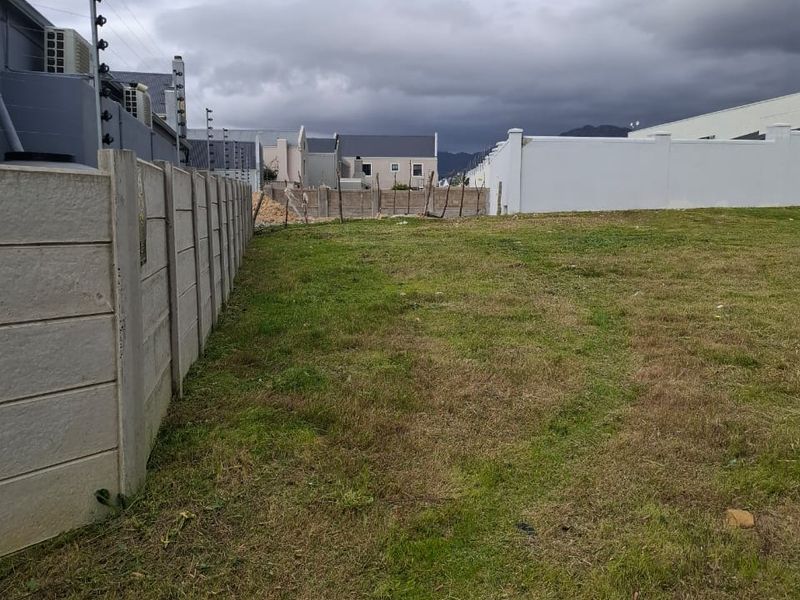 A vacant residential plot featuring a precast concrete boundary wall with installed electric fencing, offering a clear view of the surrounding neighborhood.