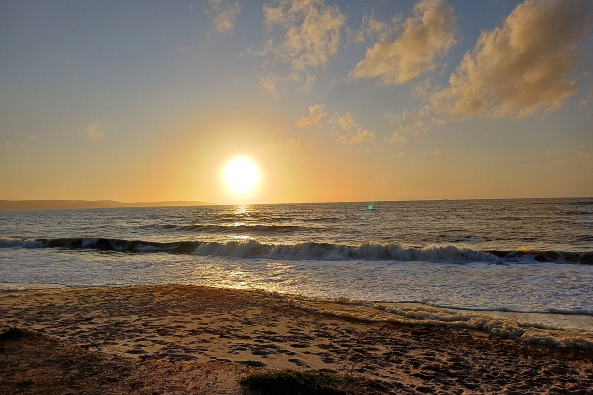 A scenic view of the ocean at sunset, showcasing the natural landscape and coastal frontage of the property.