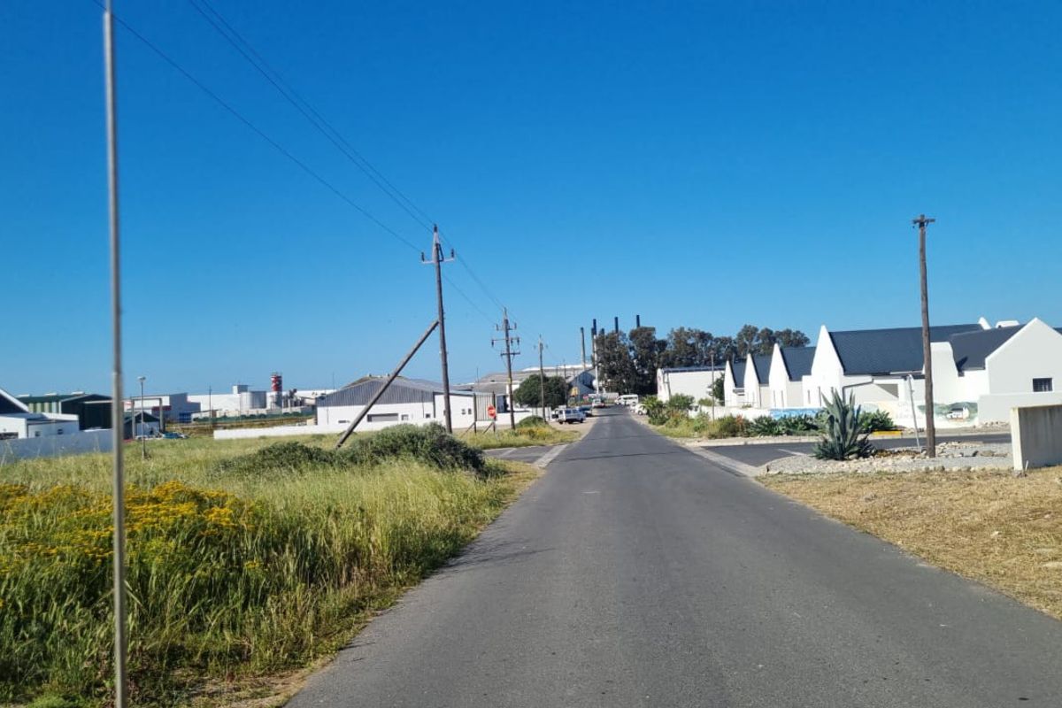 A view of the street leading towards the residential area, showing surrounding infrastructure and local landscape.