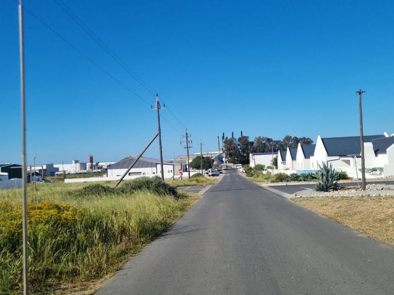 A view of the street leading towards the residential area, showing surrounding infrastructure and local landscape.