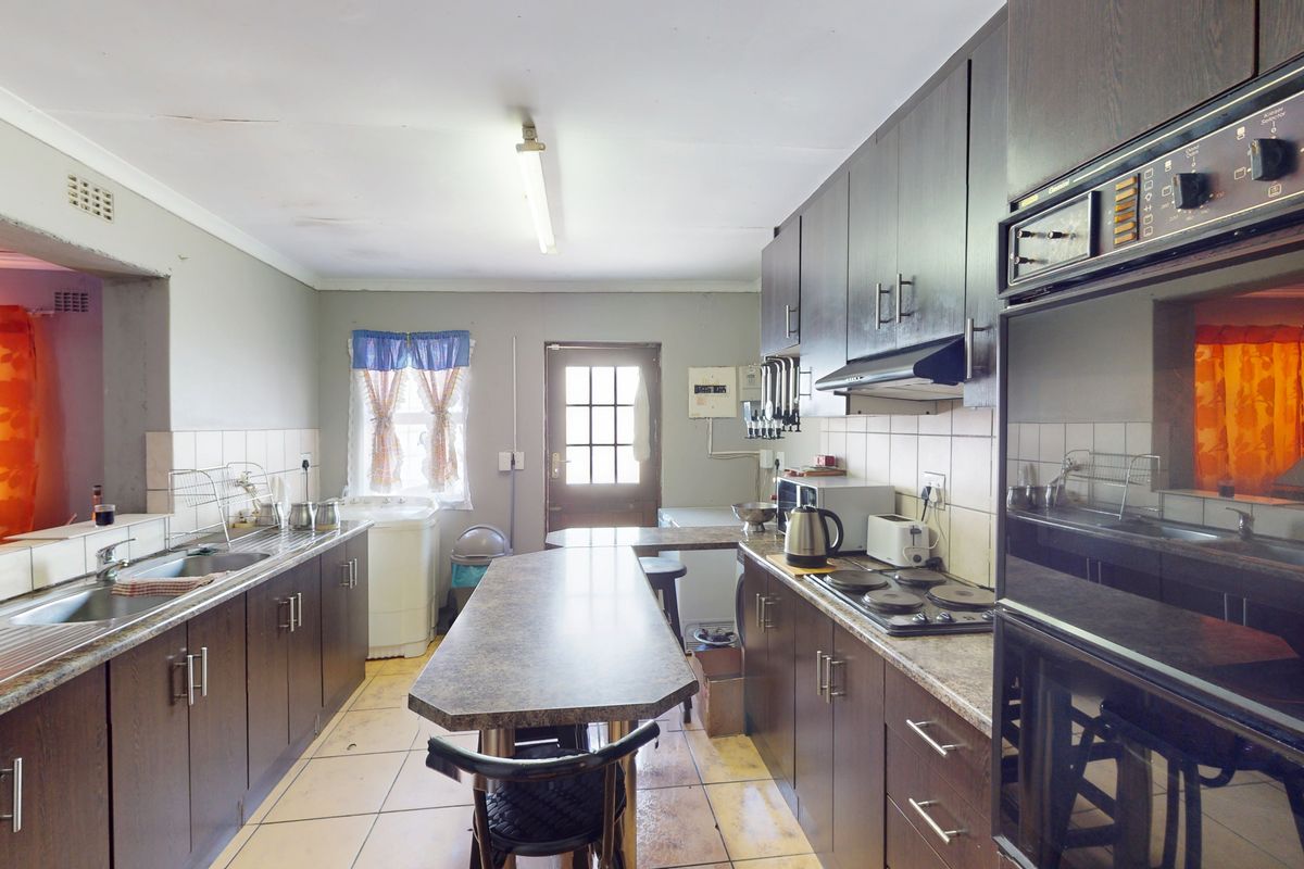 A functional kitchen featuring dark cabinetry, laminate countertops, built-in oven, and hob, with tiled flooring and a tiled backsplash.