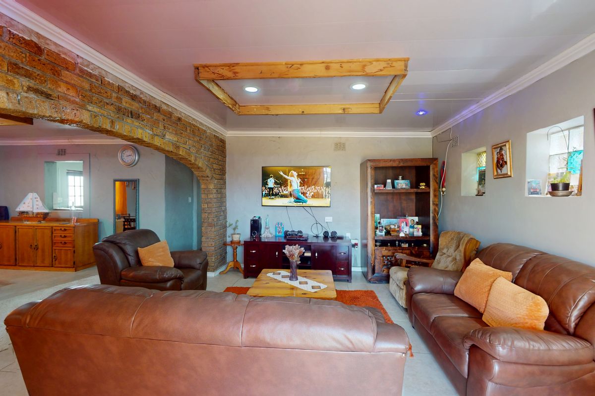 Spacious living room featuring a distinctive exposed brick archway, recessed ceiling detail, and neutral tiled flooring, creating a warm and inviting atmosphere.