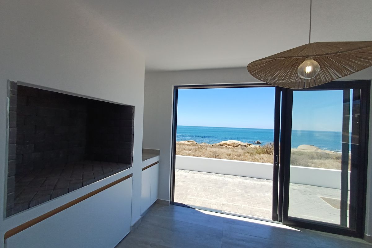 Modern living area featuring a built-in fireplace, sleek cabinetry, and large sliding doors opening to a patio with stunning ocean views.