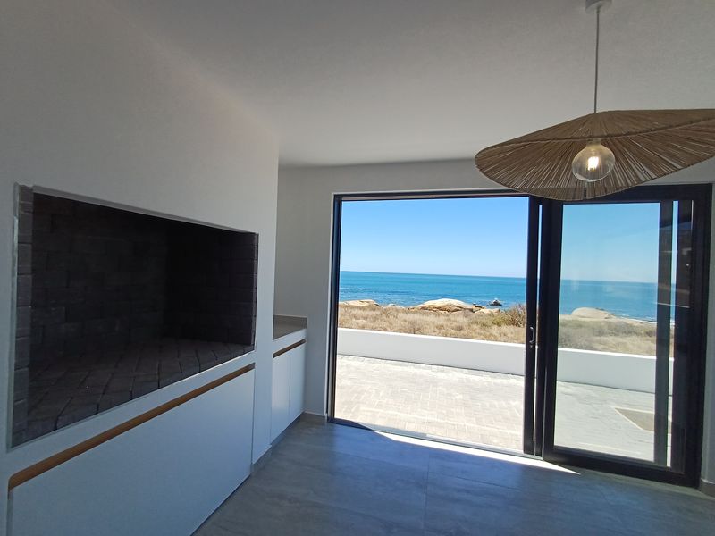Modern living area featuring a built-in fireplace, sleek cabinetry, and large sliding doors opening to a patio with stunning ocean views.