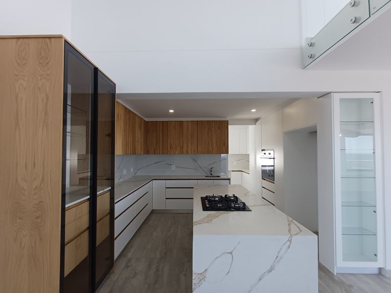 Modern kitchen featuring a central island with gas cooktop, stone countertops, integrated cabinetry, and high-end finishes in a bright, open-plan space.