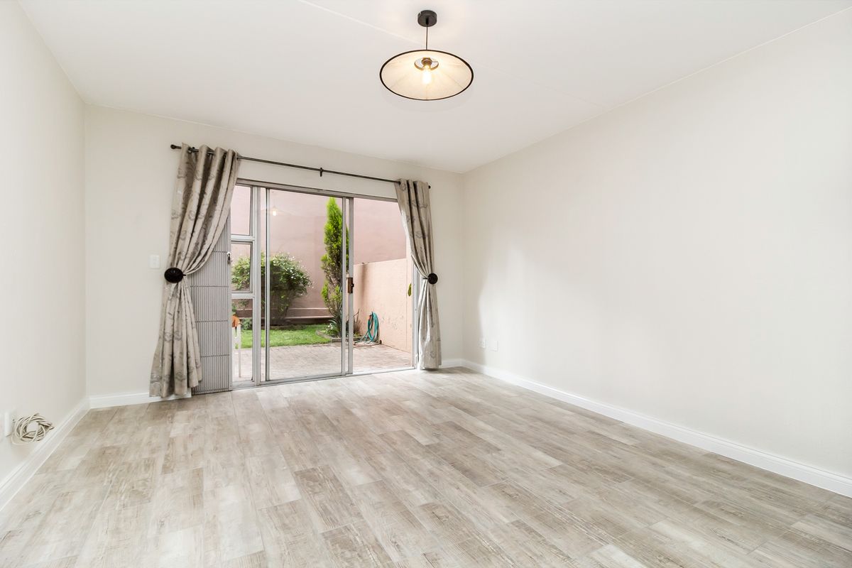 Bright and spacious living area featuring modern wood-look flooring and large sliding glass doors providing direct access to the private outdoor patio and garden.
