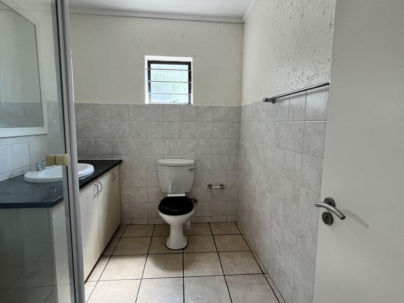 A functional bathroom featuring a shower enclosure, vanity with basin, and tiled finishes throughout.