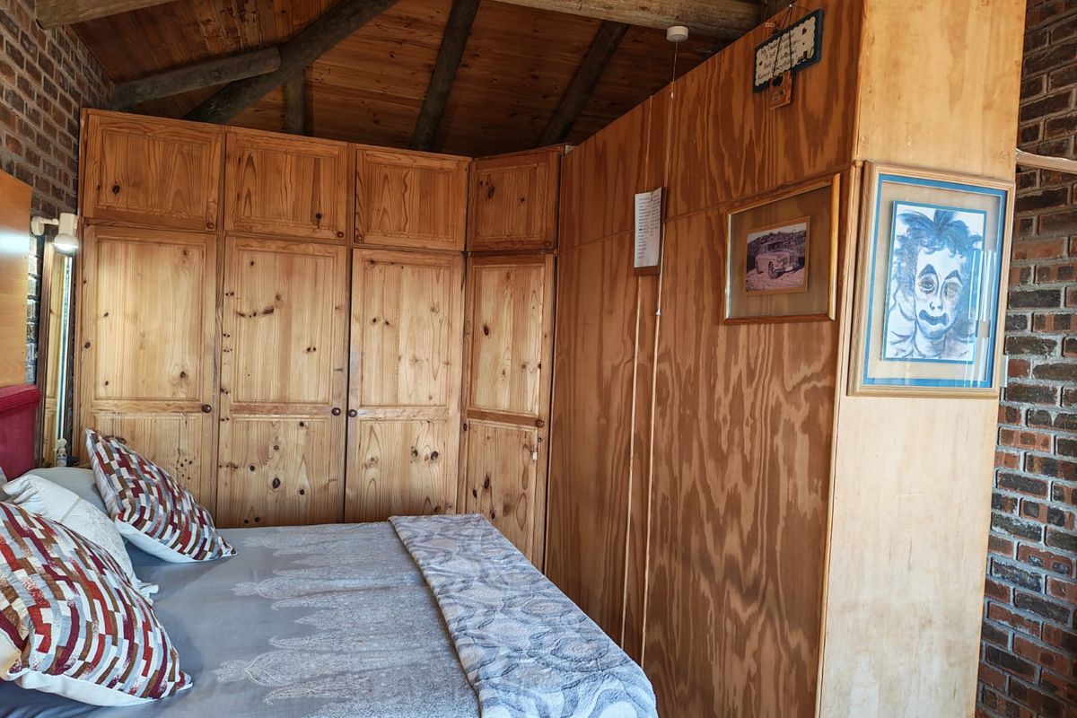 A bedroom featuring exposed timber ceiling beams, rustic brick walls, and extensive built-in wooden cabinetry providing ample storage space.