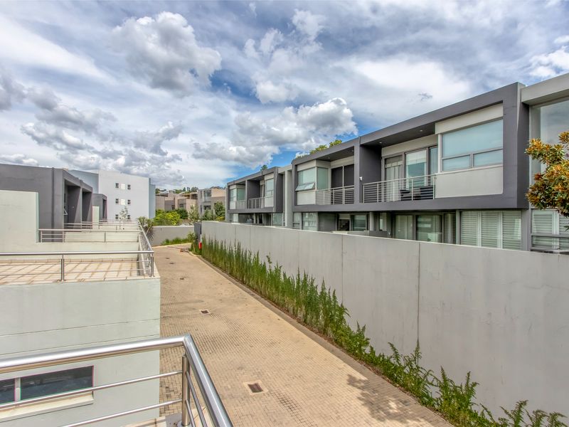 View of a modern residential complex featuring paved driveway, contemporary multi-story townhouses with balconies, and clean architectural lines.