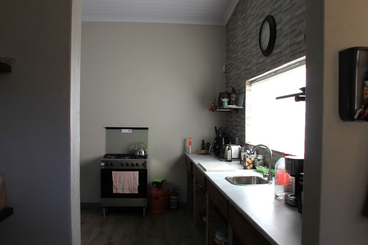 A functional kitchen area featuring a gas stove, stainless steel sink, and stone-look feature wall tiling.