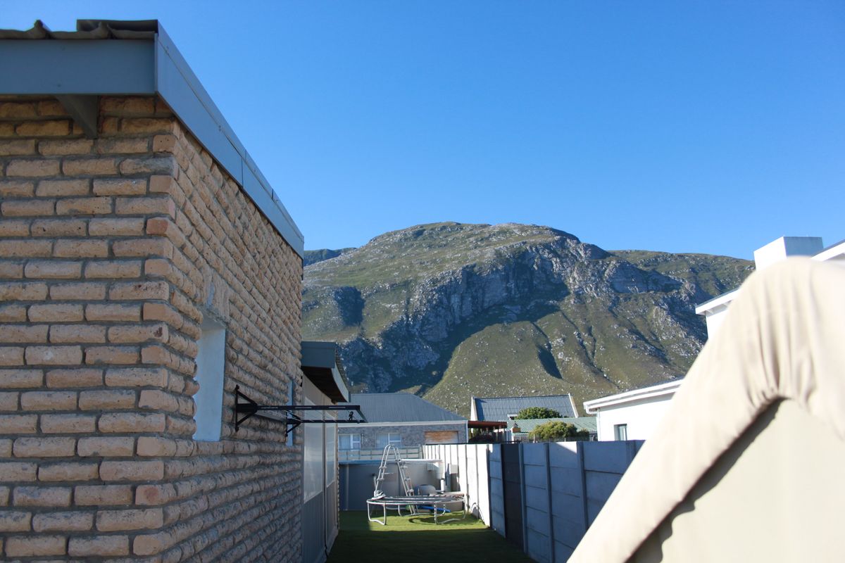 Exterior view of the property side elevation featuring exposed brickwork, with a clear view of the surrounding mountain landscape.