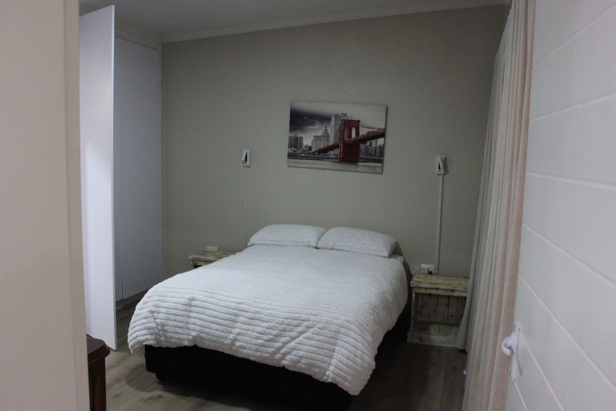 A bedroom featuring built-in cupboards, laminate flooring, and wall-mounted lighting fixtures.