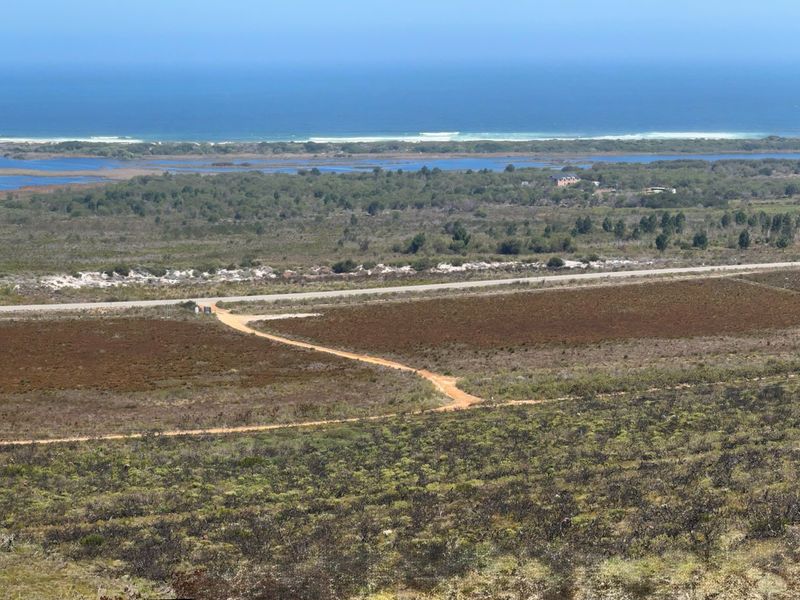 Panoramic elevated view of the farm landscape, surrounding natural vegetation, and distant coastline.