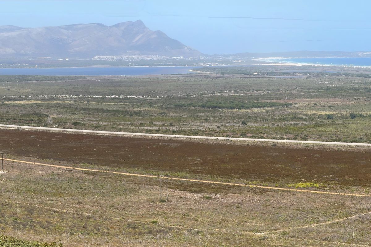 Panoramic landscape view showcasing the expansive farm terrain, surrounding natural vegetation, distant mountains, and coastal scenery.
