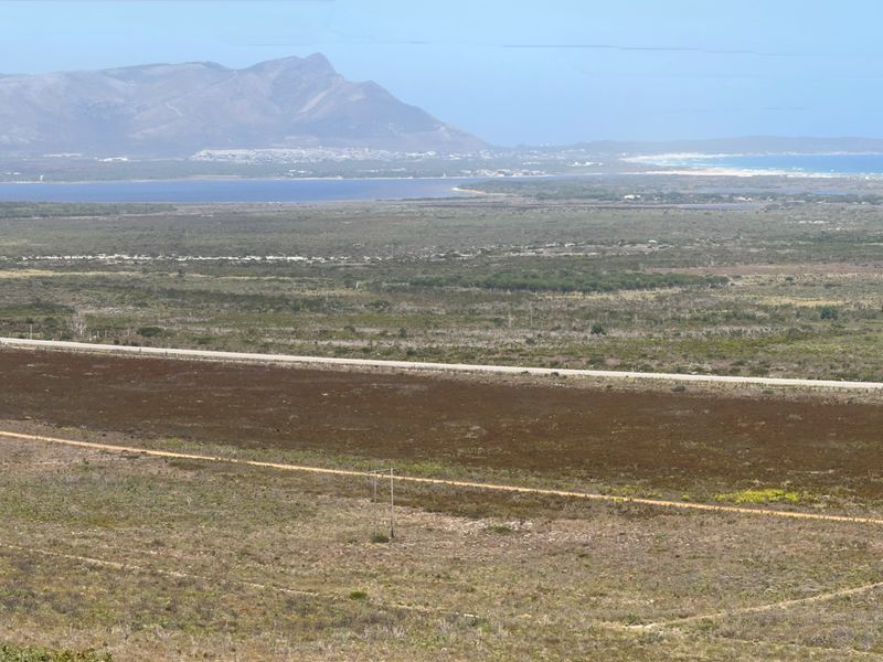 Panoramic landscape view showcasing the expansive farm terrain, surrounding natural vegetation, distant mountains, and coastal scenery.