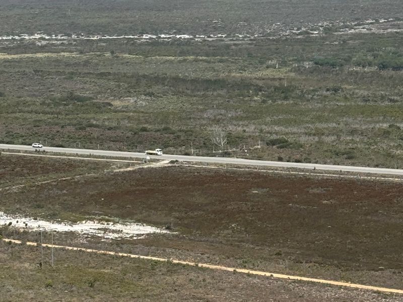 An elevated landscape view showcasing the surrounding rural terrain, distant coastline, and regional road infrastructure.