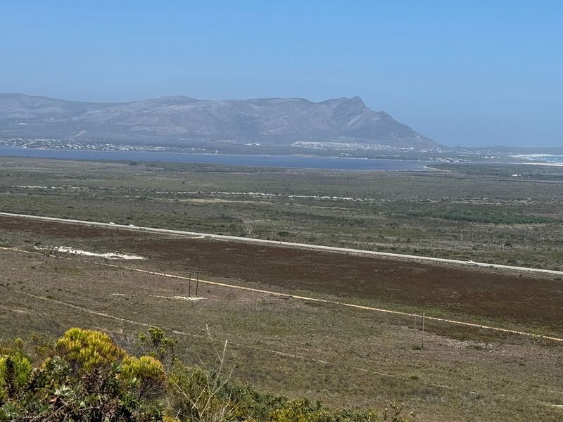 A scenic elevated landscape view overlooking the surrounding farm terrain, distant wetlands, and mountain range.