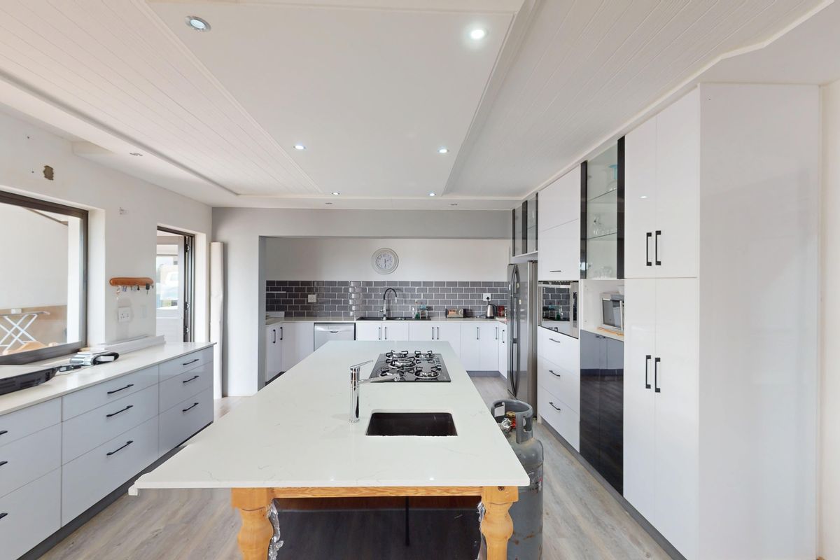Modern kitchen featuring a large central island with a built-in gas hob, stone countertops, ample cabinetry, and recessed ceiling lighting.