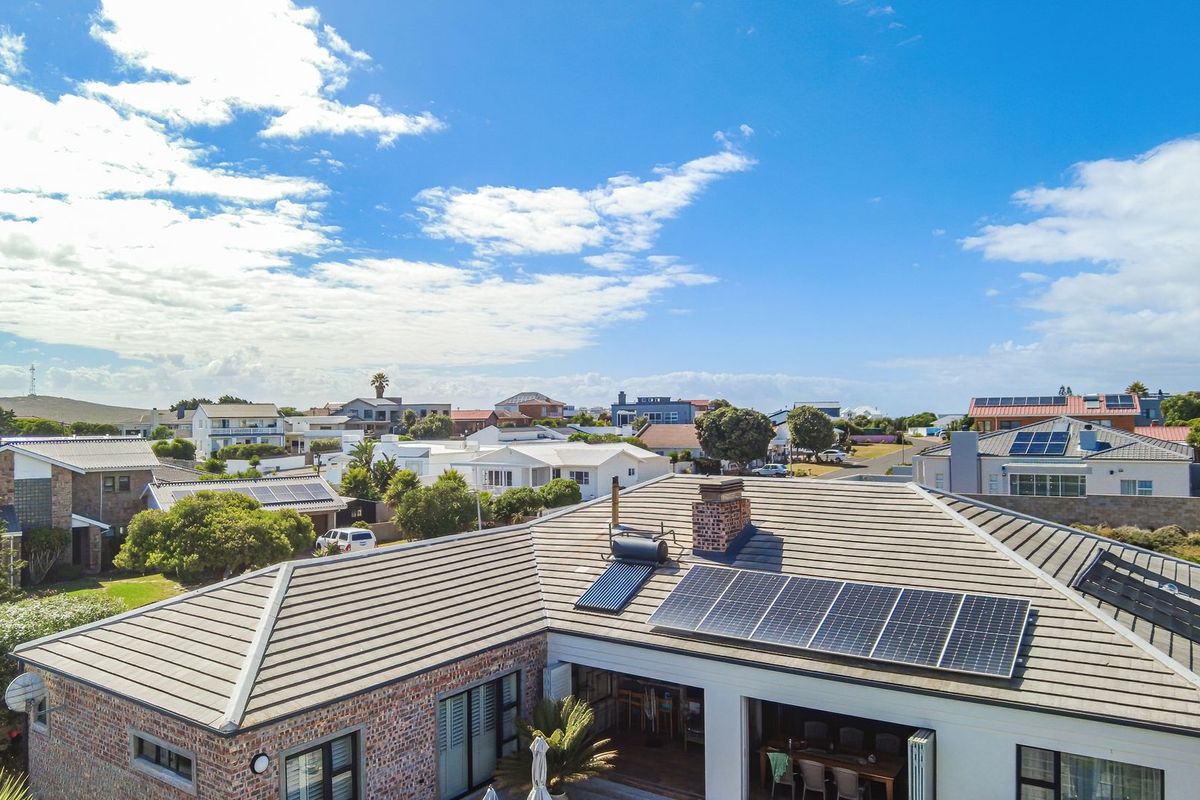 Aerial view of the property roof featuring installed solar panels and a solar water heating system, overlooking the surrounding residential neighbourhood.