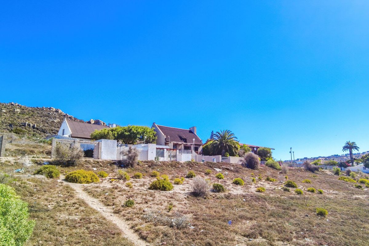 A view of the residential property exterior, showcasing the sloping landscape and surrounding terrain.