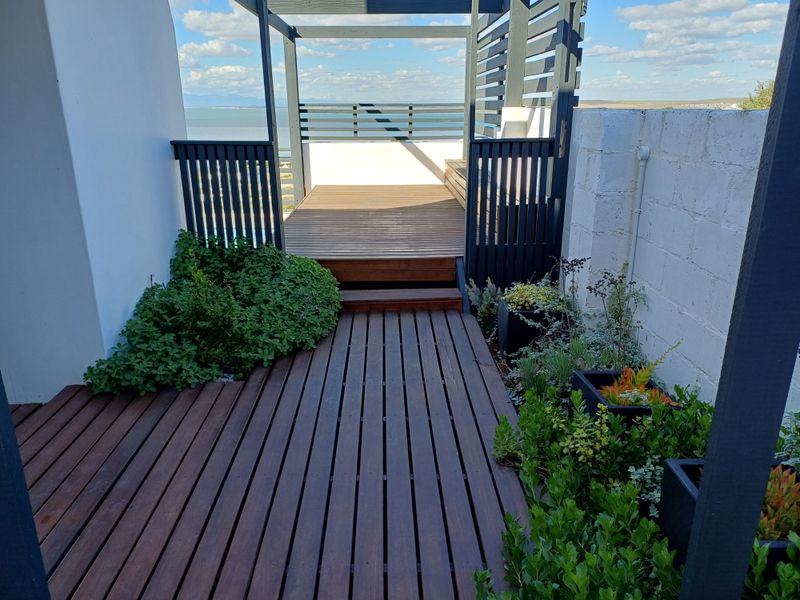 A well-maintained timber deck patio featuring a pergola and privacy screening, offering an elevated outdoor space with scenic views.