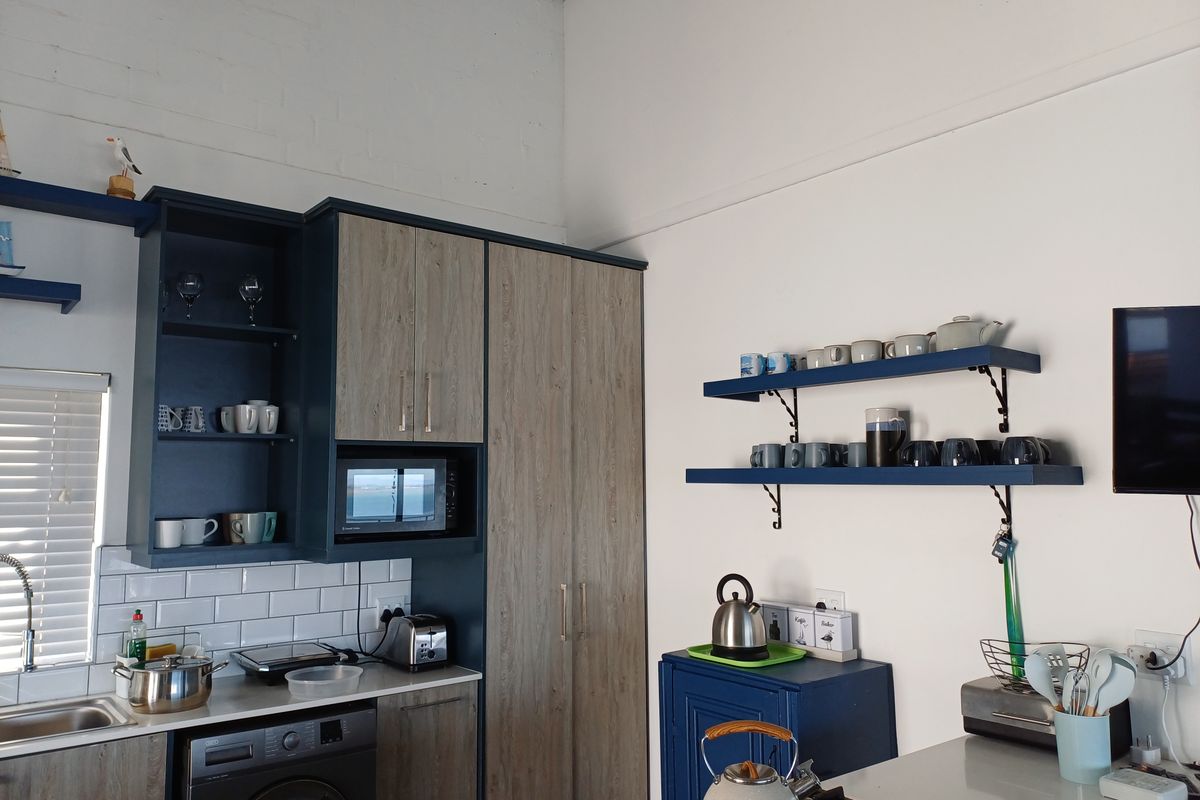 Modern kitchen featuring two-tone cabinetry, subway tile backsplash, integrated microwave, gas cooktop, and open shelving with high ceilings.