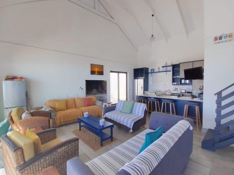 Spacious open-plan living area featuring a vaulted ceiling, built-in fireplace, and a modern kitchen with a central island and breakfast bar.