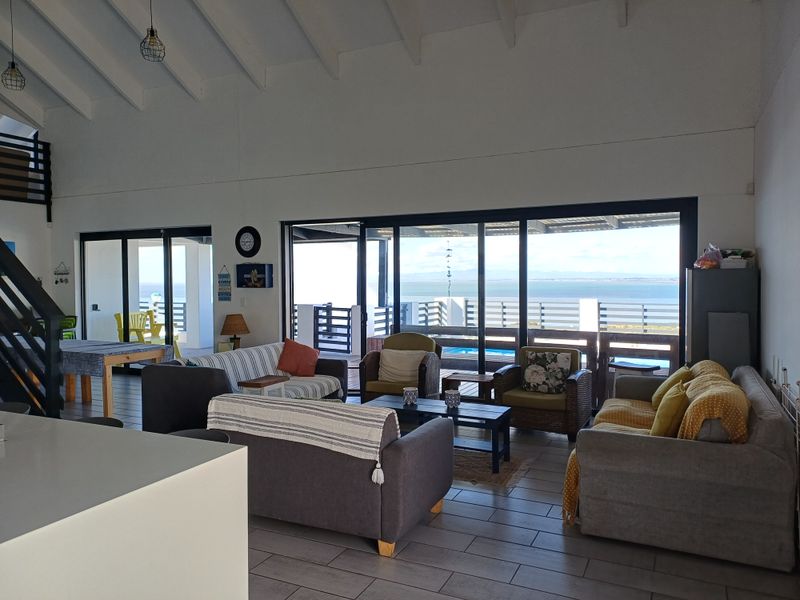Spacious open-plan living area featuring vaulted ceilings with exposed rafters, tiled flooring, and large sliding glass doors opening to a scenic outdoor view.