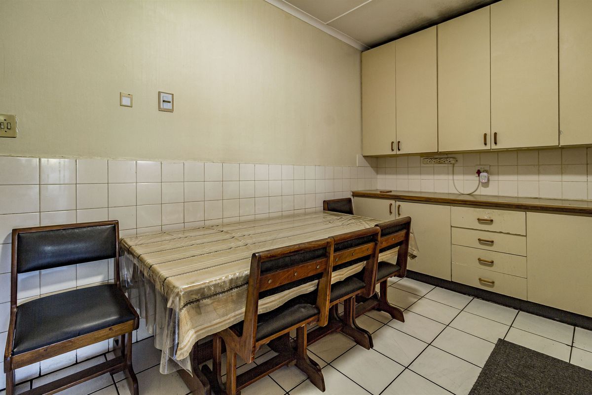 A dated kitchen area featuring tiled walls, laminate countertops, and built-in cabinetry with ample storage space.