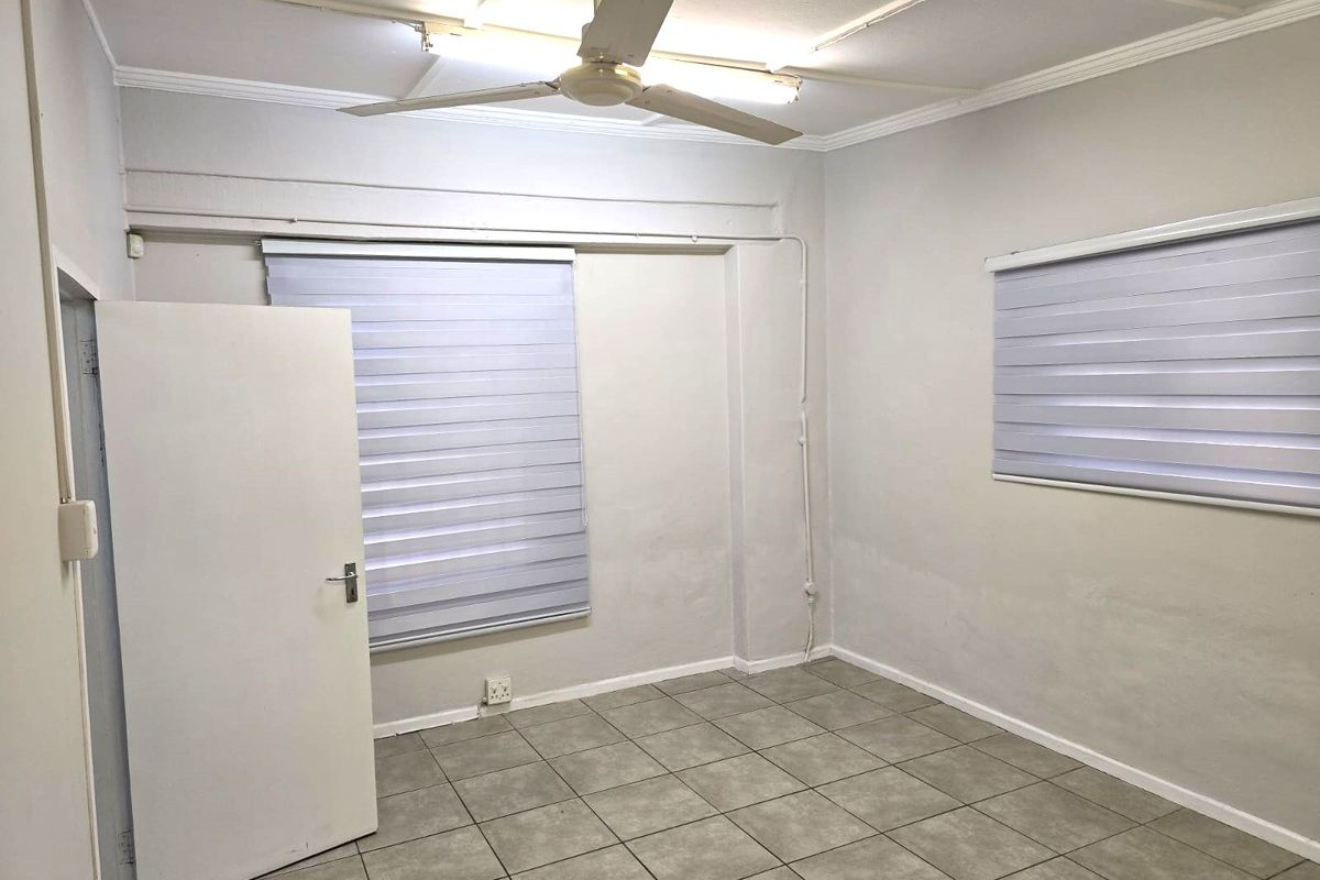 An empty bedroom featuring tiled flooring, a ceiling fan, and modern roller blinds, providing a neutral canvas for personalization.