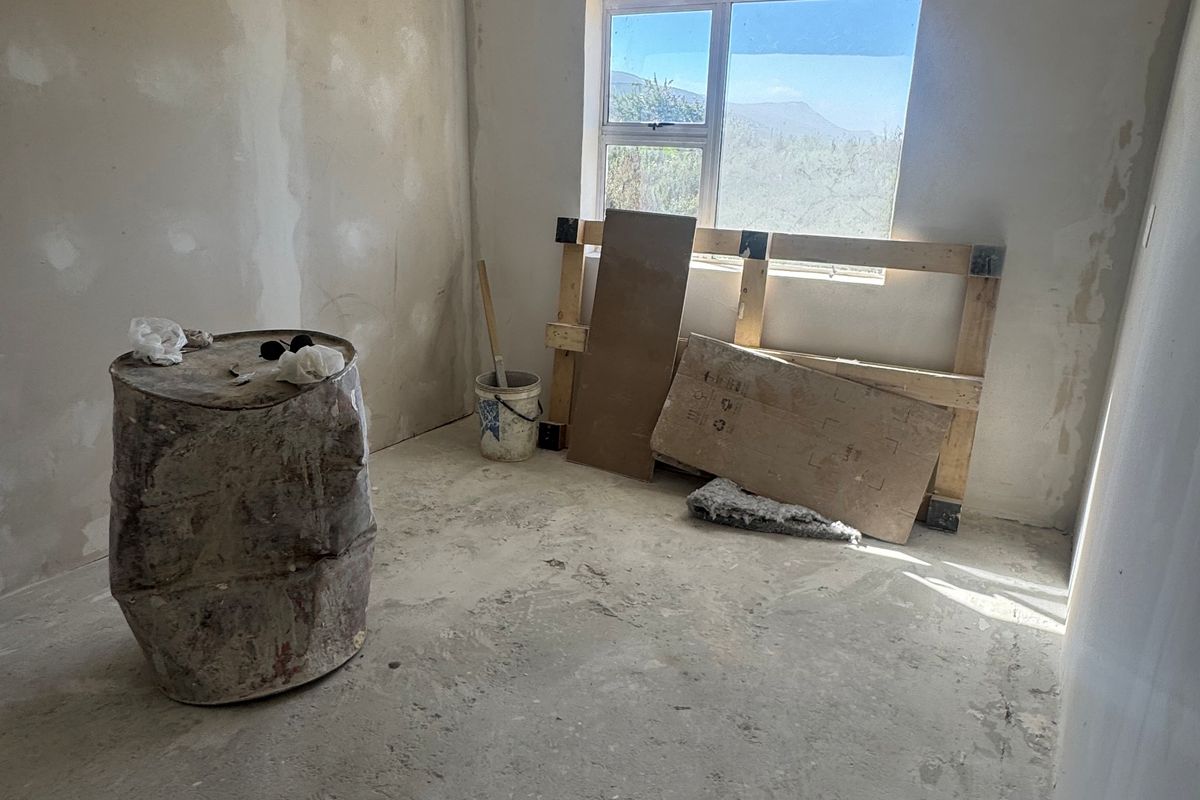 An unfinished bedroom space featuring raw concrete flooring and unpainted plaster walls, offering a blank canvas for renovation and custom interior finishes.