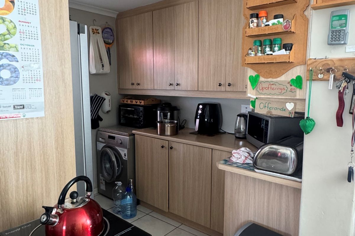 Compact kitchen featuring light wood-look cabinetry, tiled flooring, and integrated space for a washing machine, providing a functional and efficient culinary workspace.