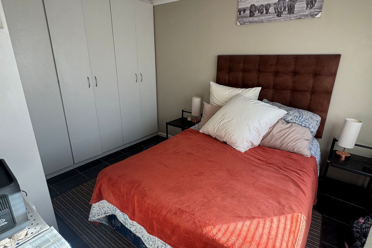 A functional bedroom featuring built-in cupboards and tiled flooring, providing a practical and comfortable living space.