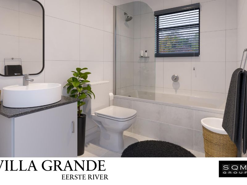 Modern bathroom featuring a vessel sink vanity, toilet, and a bathtub with a glass shower screen and tiled finishes.