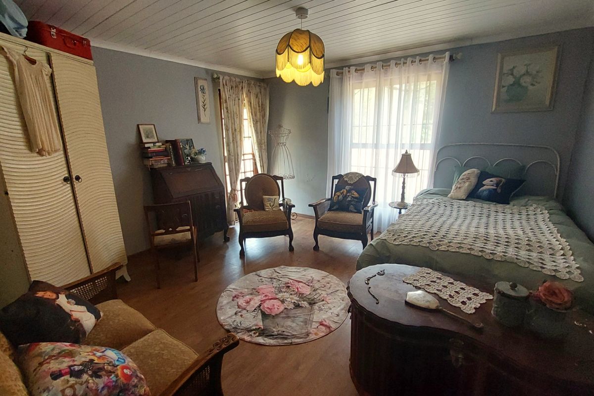 A cozy bedroom featuring wood-look flooring, a tongue-and-groove ceiling, and large windows that provide natural light.