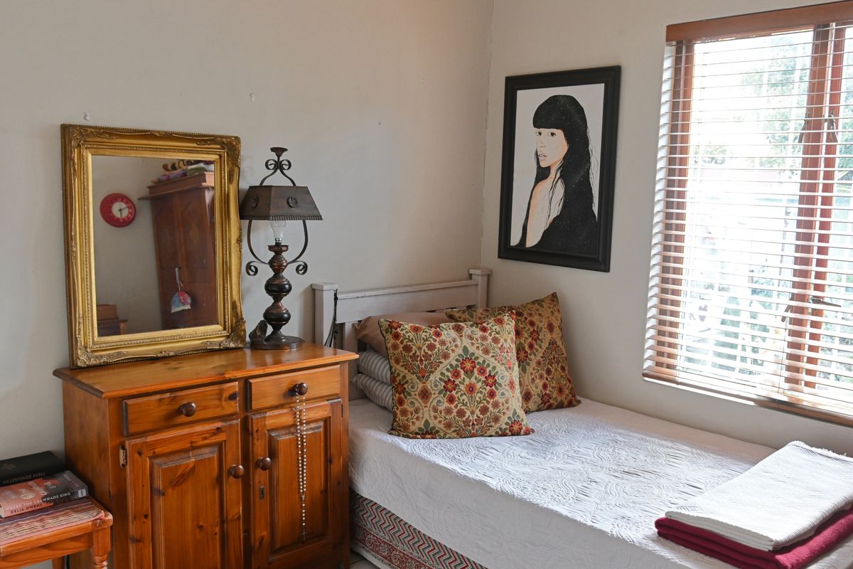 A cozy bedroom featuring a window with fitted wooden blinds and neutral wall finishes.