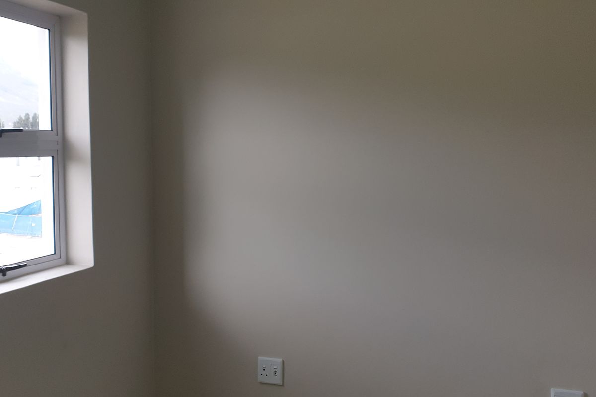 A clean, empty bedroom featuring neutral walls and an aluminium-framed window, providing a blank canvas for personalization.