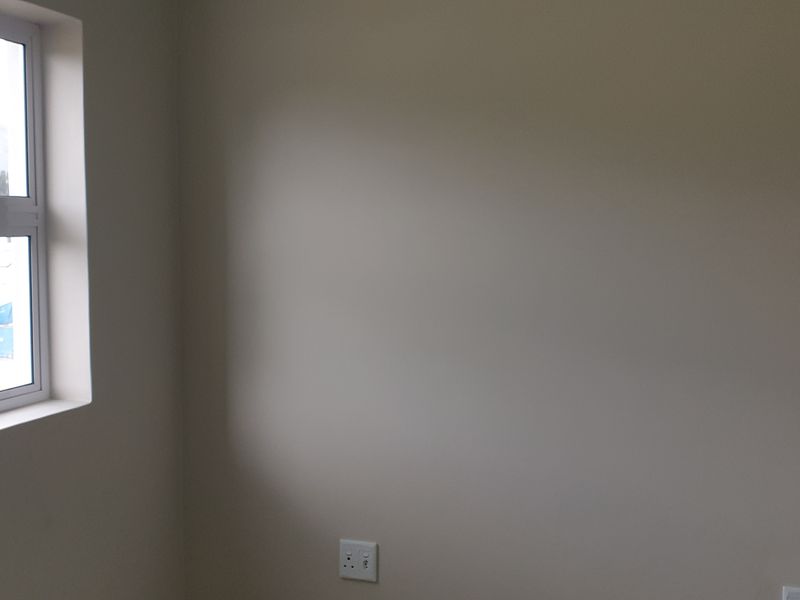 A clean, empty bedroom featuring neutral walls and an aluminium-framed window, providing a blank canvas for personalization.