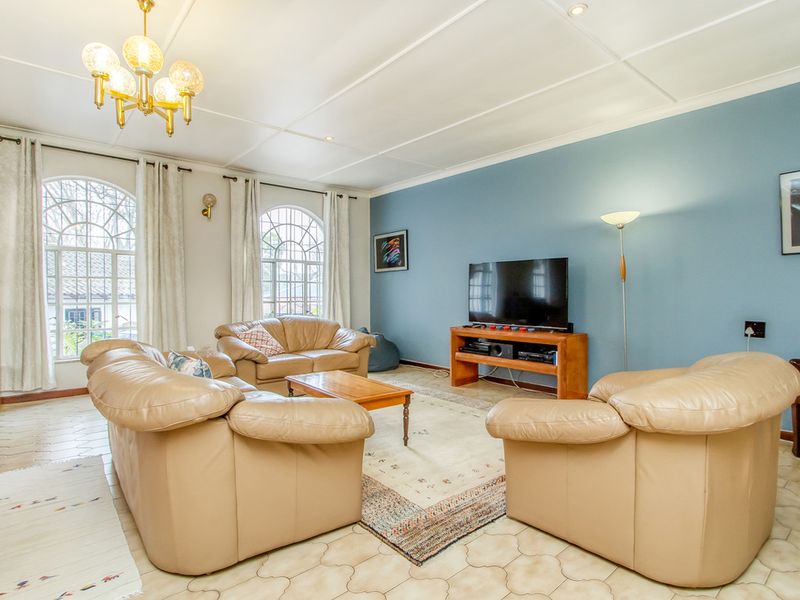 A spacious living room featuring arched windows, tiled flooring, and a feature wall, providing a comfortable and well-lit area for relaxation.