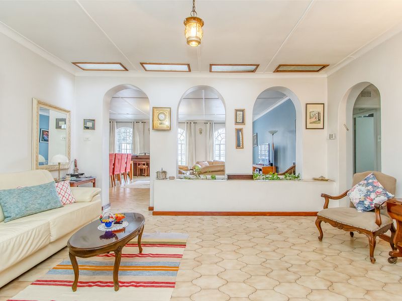 Spacious living area featuring distinctive arched wall openings, tiled flooring, and recessed ceiling panels, creating an open and connected layout.