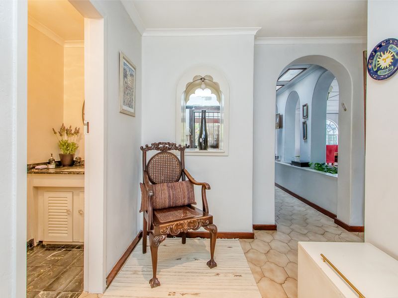 A bright hallway featuring arched architectural details, tiled flooring, and a built-in vanity area visible through the doorway.