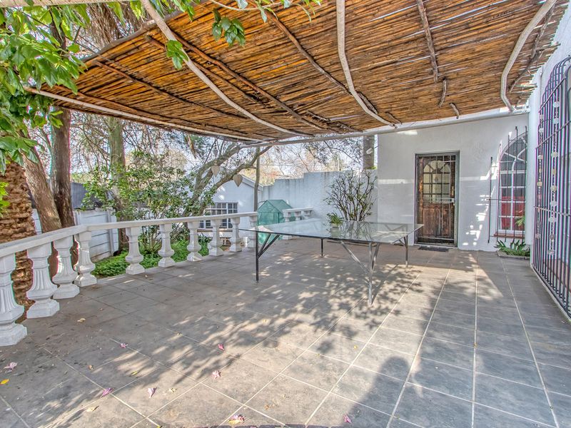 Covered patio area featuring tiled flooring, a rustic reed roof structure, and decorative balustrades, providing a shaded outdoor space for relaxation.