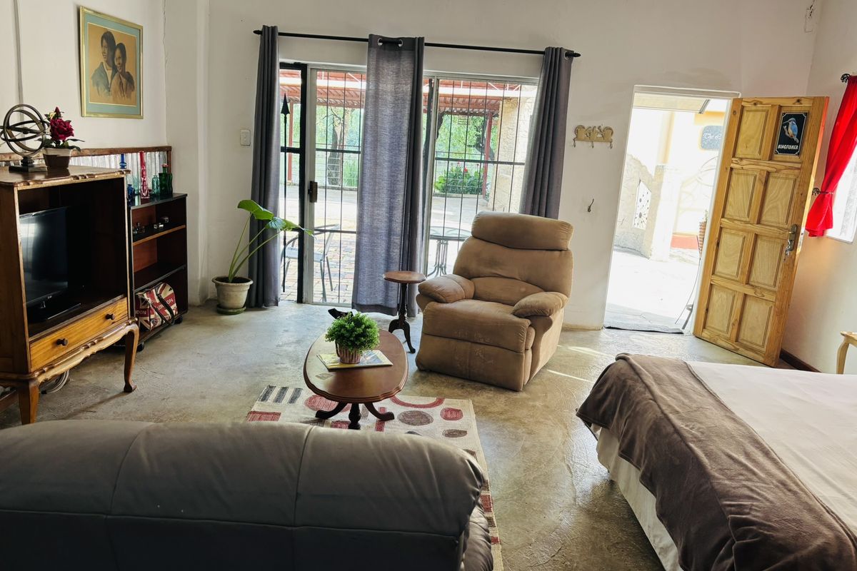 A living area featuring concrete flooring, sliding glass doors leading to an outdoor space, and a wooden door providing additional access.